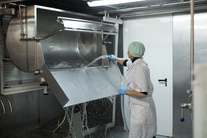 Woman cleaning machine at a food production facility