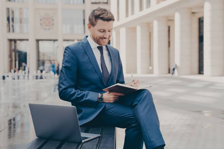 A smiling document controller writing in a notepad after regulatory affairs training