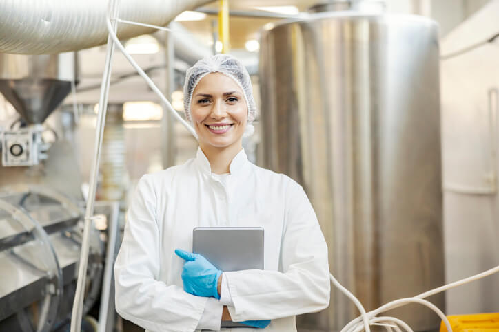 A smiling female quality control specialist at a manufacturing plant after completing her quality assurance training