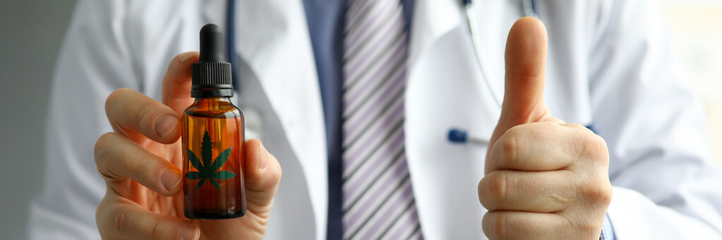 A male professional giving the thumbs-up sign to a CBD oils jar after completing his cannabis courses