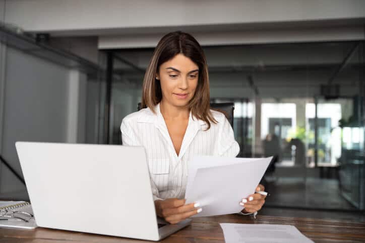 A focused female clinical research professional analyzing a project charter document in an office