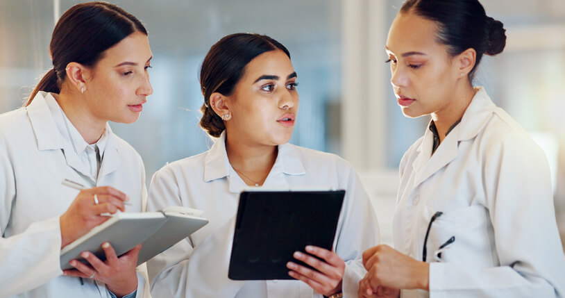 Focused female students engaging in clinical research training on a tablet.